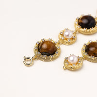 Ornate gold-plated bracelet with alternating brown tiger's eye stones and white freshwater pearls in crystal-accented settings