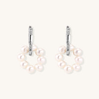 Sterling silver huggie hoop earrings with clustered white freshwater pearls and crystal accents on white background.