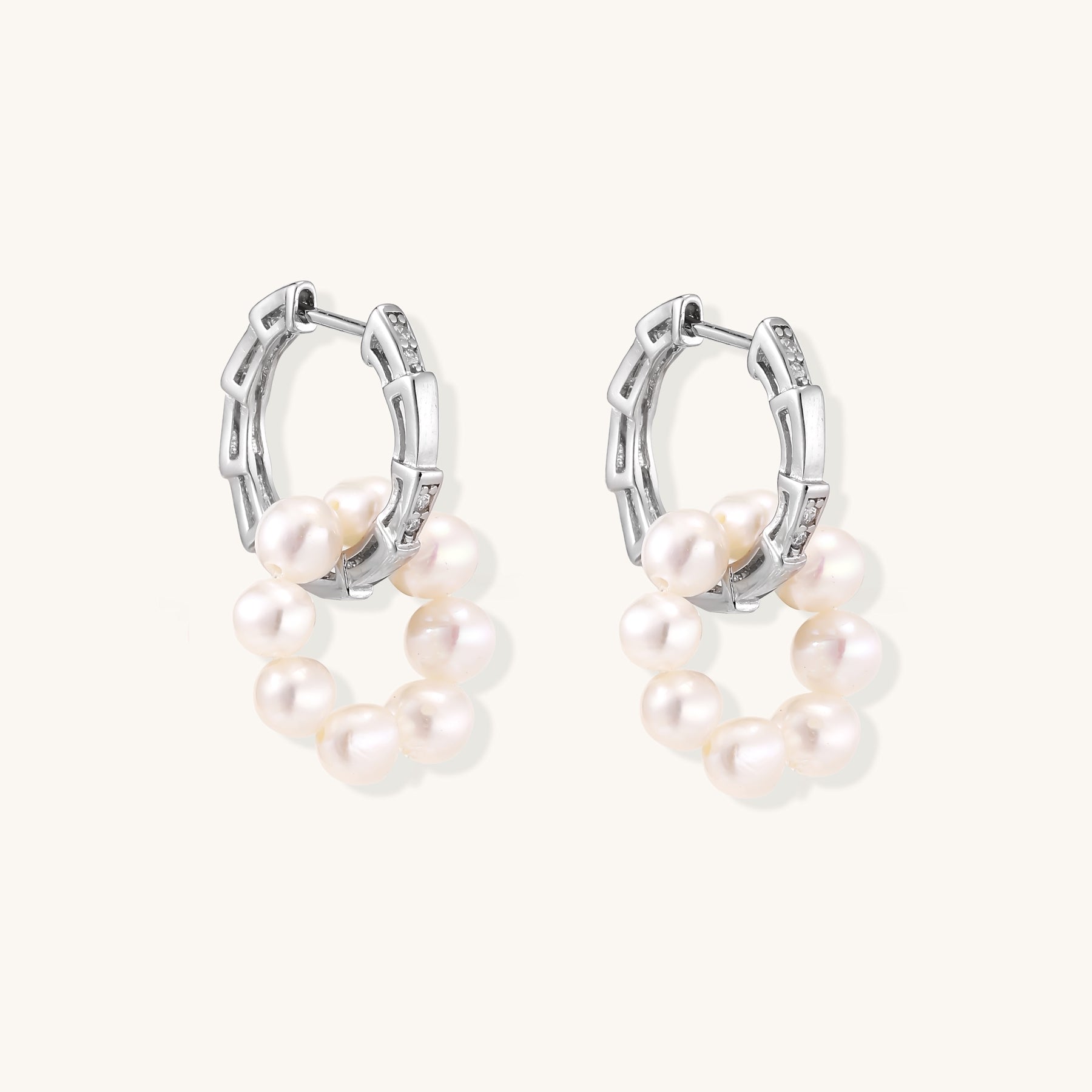 Sterling silver huggie hoop earrings with clustered white freshwater pearls and crystal accents on white background.