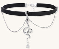 Black leather choker with gold-plated serpent pendant and crystal droplet on white background, adjustable chain design
