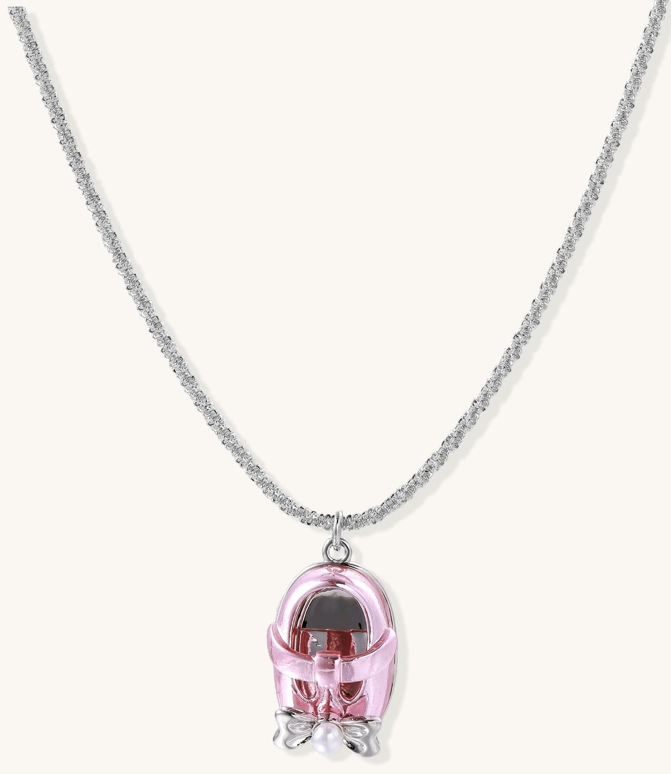 Delicate gold-plated chain necklace with transparent pink-tinted capsule pendant containing decorative bow element