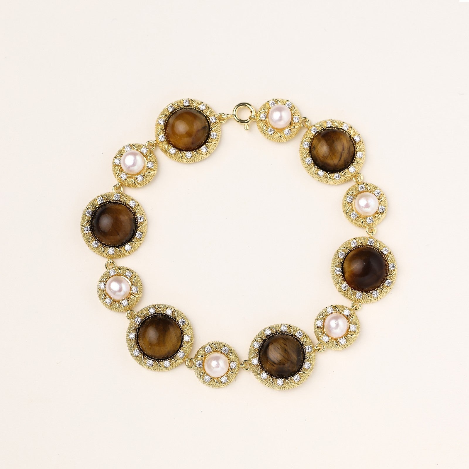 Ornate gold-plated bracelet with alternating brown tiger's eye stones and white freshwater pearls in crystal-accented settings