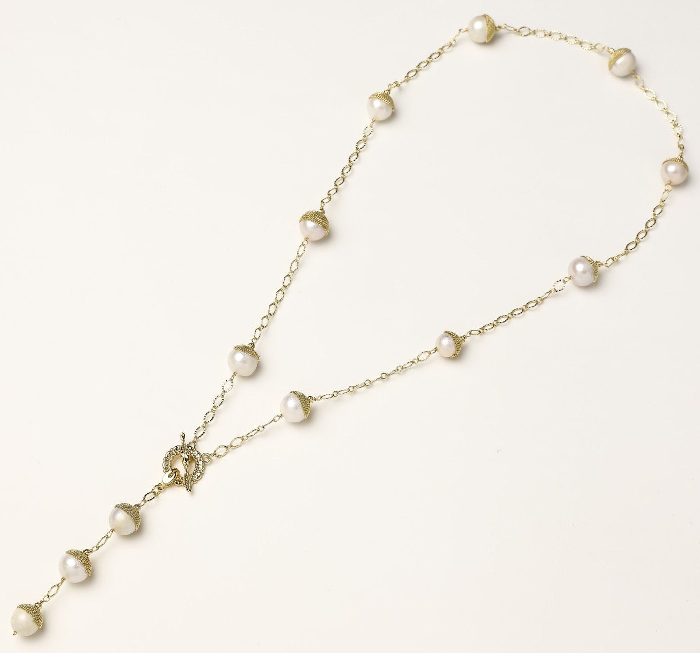Long gold-plated lariat necklace featuring baroque pearls with metal caps arranged in elegant Y-shape design