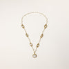 Long gold-plated necklace with eye-shaped elements, freshwater pearls, and baroque pearl pendant on neutral background.