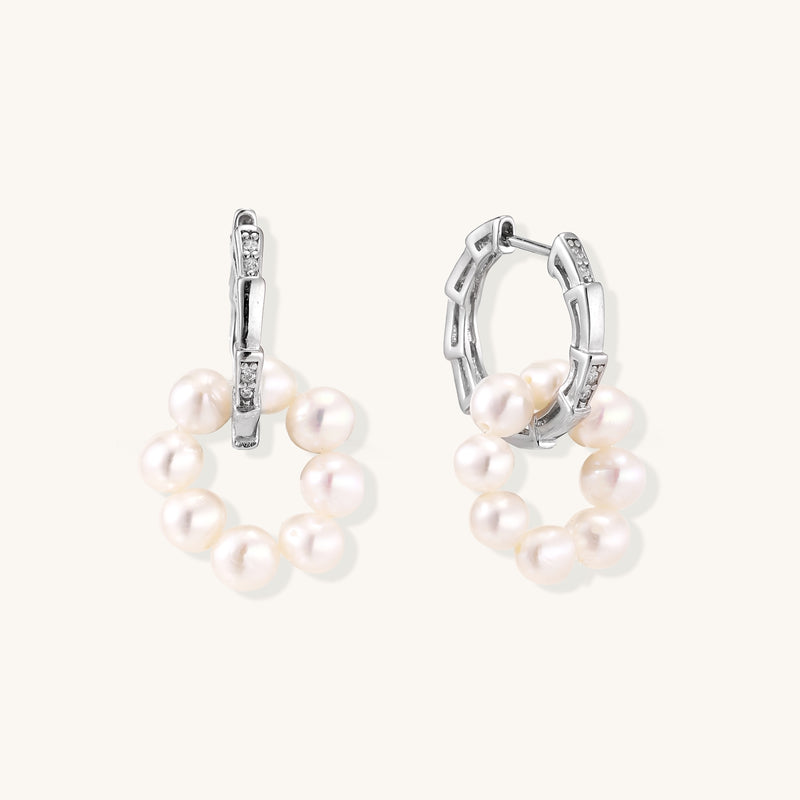 Sterling silver huggie hoop earrings with clustered white freshwater pearls and crystal accents on white background.