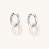 Sterling silver huggie hoop earrings with clustered white freshwater pearls and crystal accents on white background.