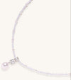 Delicate beaded necklace with lavender crystals, white pearls, and crystal pendant with pearl drop on white background.
