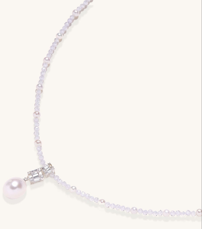 Delicate beaded necklace with lavender crystals, white pearls, and crystal pendant with pearl drop on white background.