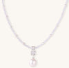 Delicate beaded necklace with lavender crystals, white pearls, and crystal pendant with pearl drop on white background.