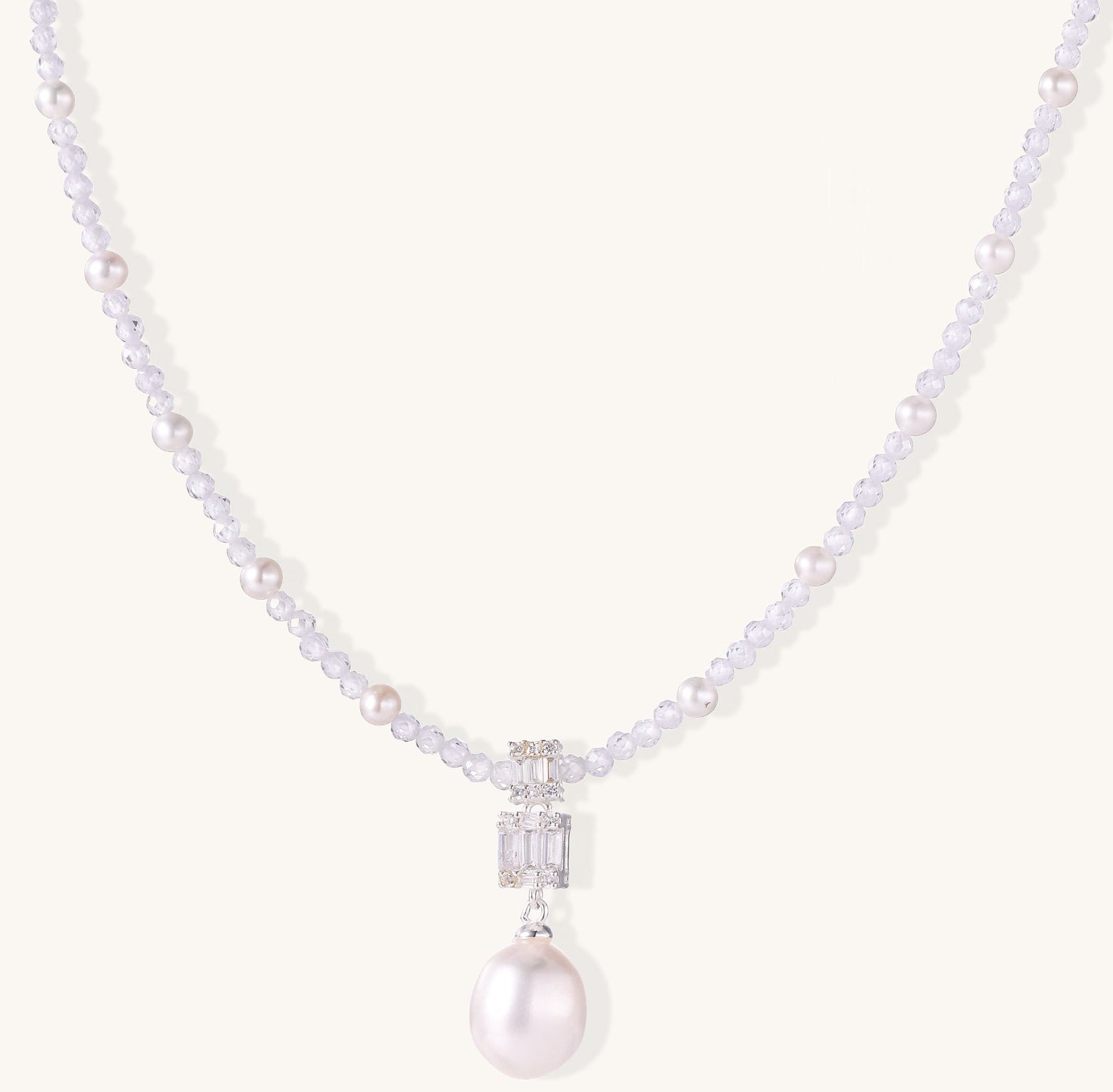 Delicate beaded necklace with lavender crystals, white pearls, and crystal pendant with pearl drop on white background.