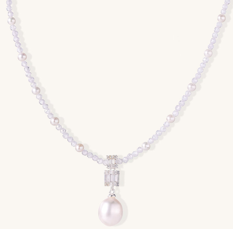 Delicate beaded necklace with lavender crystals, white pearls, and crystal pendant with pearl drop on white background.