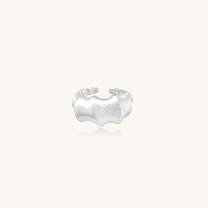Chunky sterling silver ring with organic flowing design and brushed matte finish on neutral background