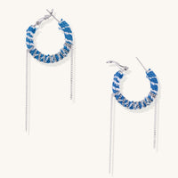 Blue and white checkered denim-wrapped hoop earrings with delicate silver chain dangles on neutral background