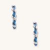 Twisted hoop earrings featuring blue denim fabric braided with gold-plated metal in a spiral design on white background.