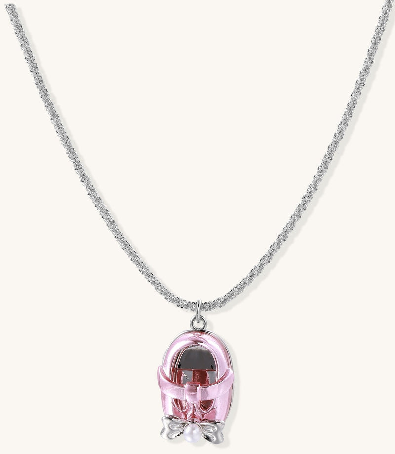 Delicate gold-plated chain necklace with transparent pink-tinted capsule pendant containing decorative bow element