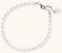 Delicate sterling silver bracelet with small freshwater pearls and adjustable chain on neutral background.