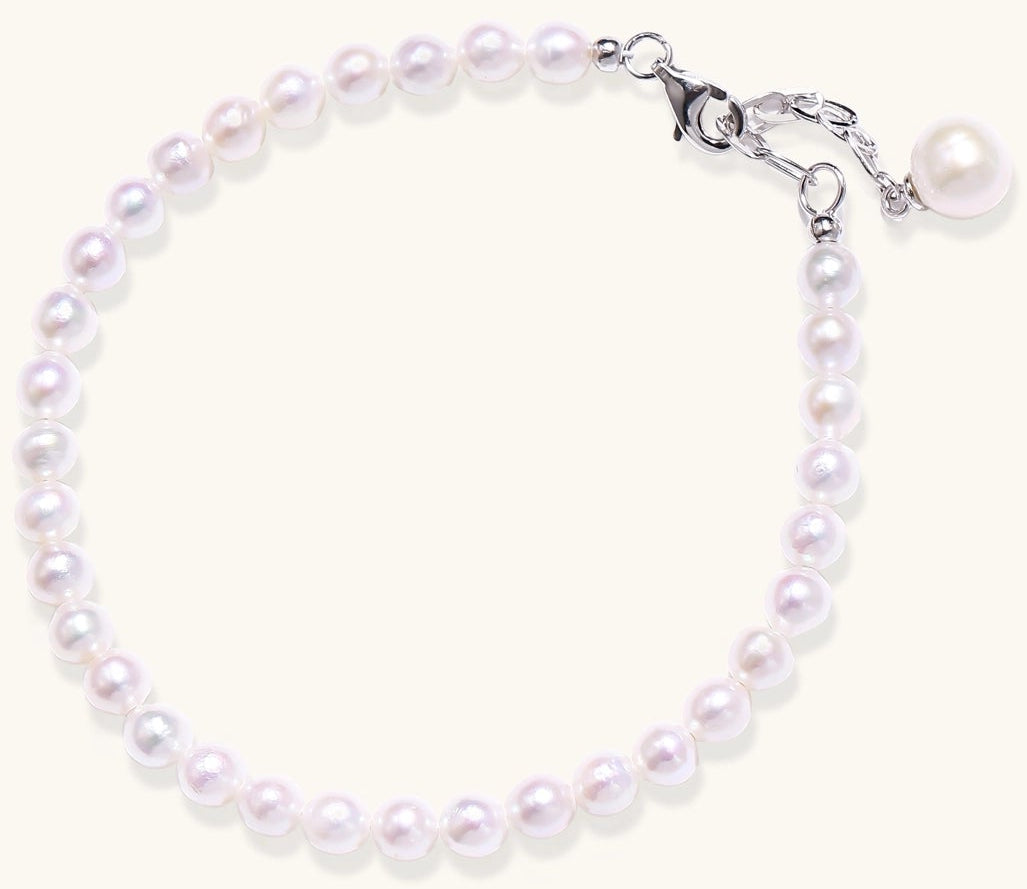 Delicate sterling silver bracelet with small freshwater pearls and adjustable chain on neutral background.