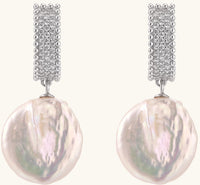 Sterling silver huggie earrings with lustrous baroque pearls displaying iridescent pink and cream tones on white background.