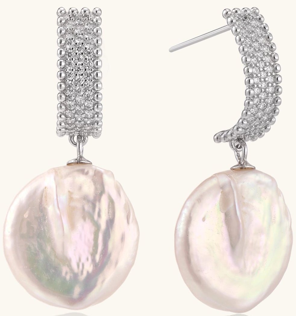 Sterling silver huggie earrings with lustrous baroque pearls displaying iridescent pink and cream tones on white background.