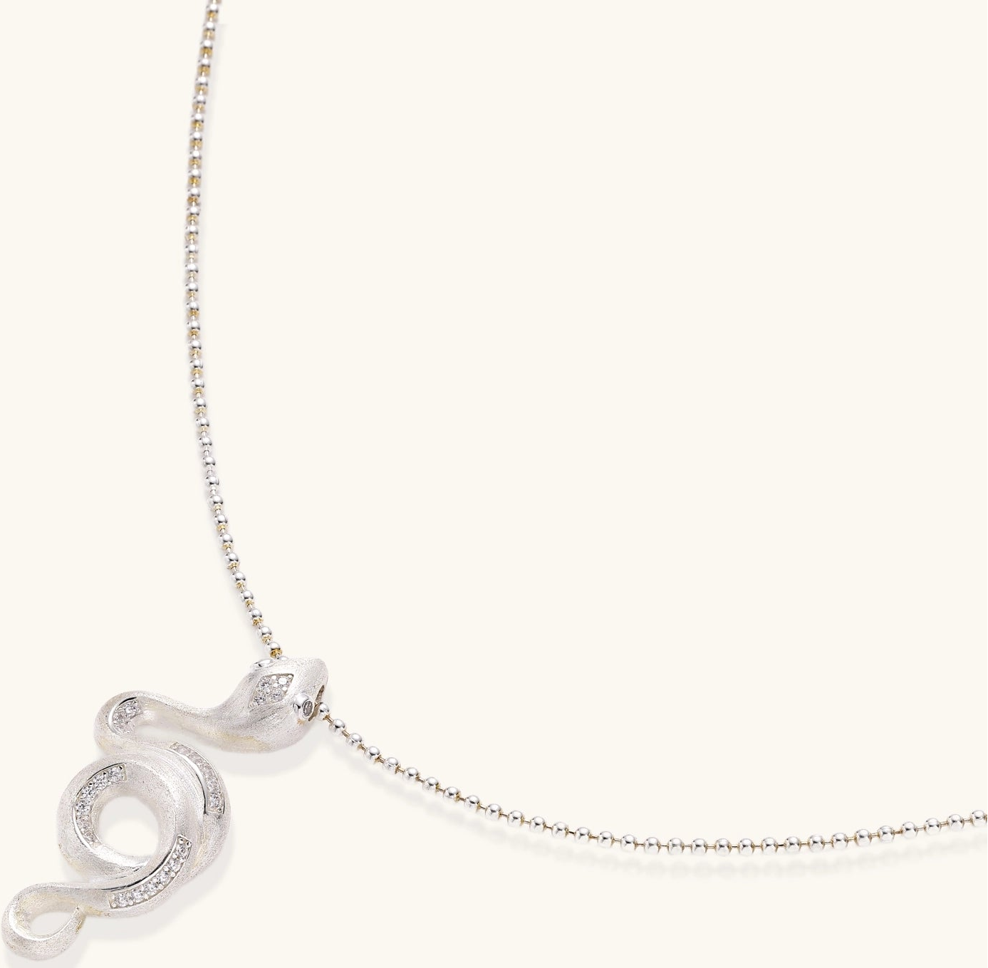 Sterling silver snake pendant necklace with zirconia crystals on adjustable chain against cream background