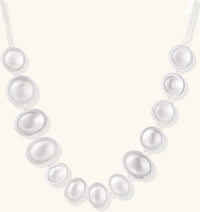 Sterling silver necklace with asymmetrically placed white pearls of varying sizes on neutral background