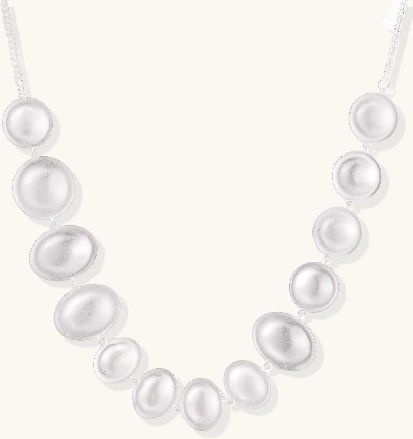 Sterling silver necklace with asymmetrically placed white pearls of varying sizes on neutral background