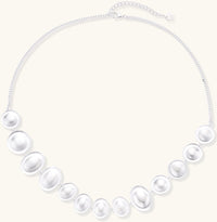 Sterling silver necklace with asymmetrically placed white pearls of varying sizes on neutral background