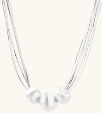 Multi-strand sterling silver necklace with three polished round beads clustered at center on white background.