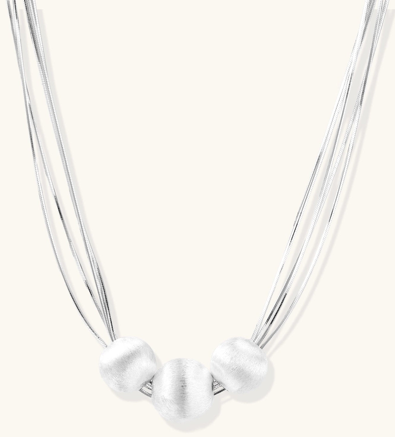 Multi-strand sterling silver necklace with three polished round beads clustered at center on white background.