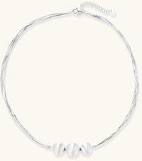 Multi-strand sterling silver necklace with three polished round beads clustered at center on white background.