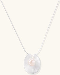 Delicate sterling silver necklace with oval iridescent pendant and central freshwater pearl on white background