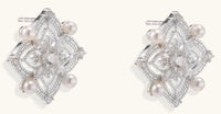 Detailed view of sterling silver stud earrings with geometric filigree design and small freshwater pearls on white background.
