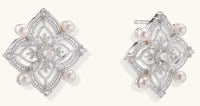 Detailed view of sterling silver stud earrings with geometric filigree design and small freshwater pearls on white background.