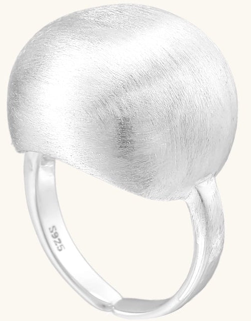 Minimalist sterling silver ring with large brushed disc top and adjustable band on white background.