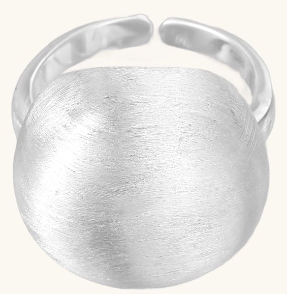 Minimalist sterling silver ring with large brushed disc top and adjustable band on white background.