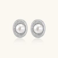 Oval rhodium-plated silver studs featuring freshwater pearls surrounded by pavé crystal halo on white background