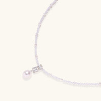 Dainty necklace with lavender crystal beads, freshwater pearls, geometric pendant, and large pearl drop on white background.
