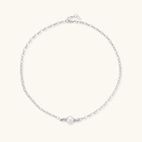 Dainty rhodium-plated silver chain necklace with centered 10mm freshwater pearl and crystal accents on cream background