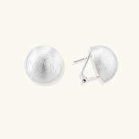 Brushed sterling silver half-dome clip-on earrings with textured surface against cream background
