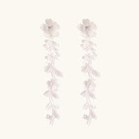 Long sterling silver drop earrings with delicate floral vine design and crystal accents on white background