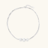 Sterling silver multi-strand necklace with three brushed round beads on cream background