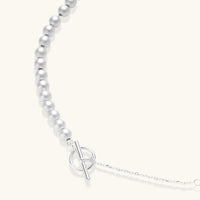 Long sterling silver beaded necklace with graduated sphere design, toggle clasp, and delicate chain extension on white background