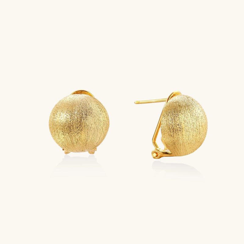 Pair of brushed gold dome earrings with clip backs showing textured matte finish on cream background