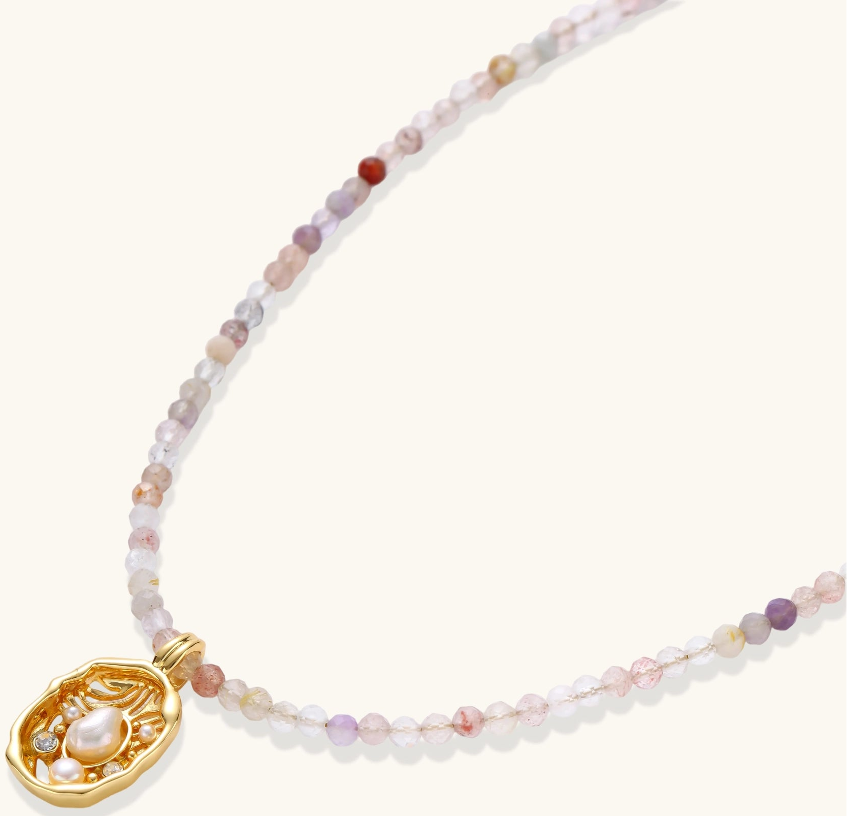 Delicate gold-plated necklace with mixed gemstone beads and ornate oval pendant on white background