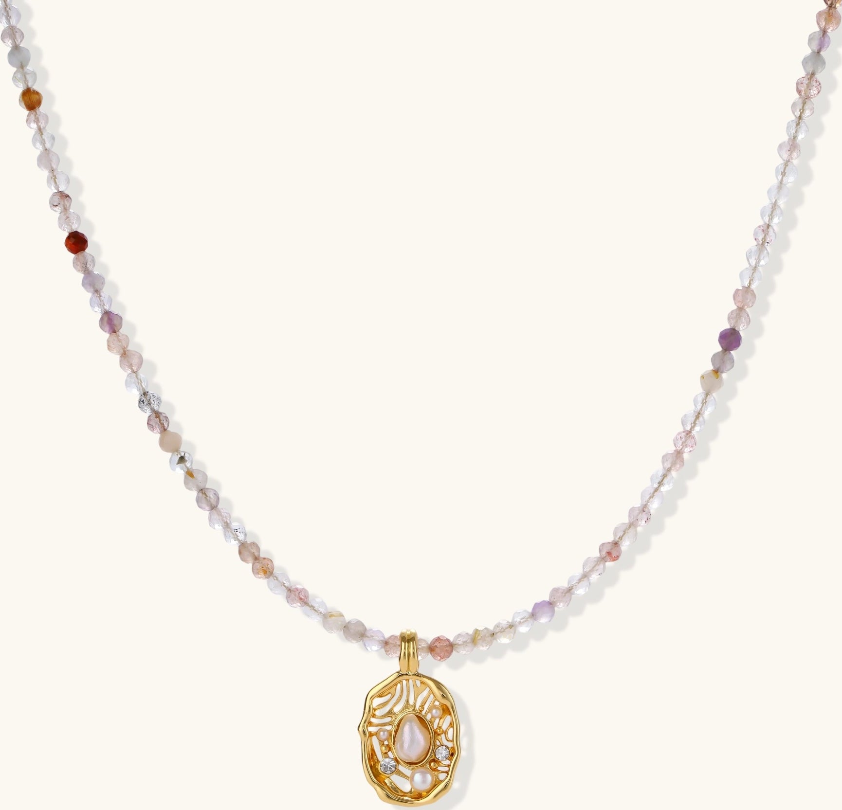 Delicate gold-plated necklace with mixed gemstone beads and ornate oval pendant on white background