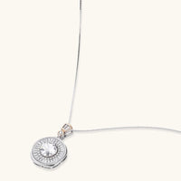 Sterling silver necklace with circular geometric pendant featuring central moissanite and radial baguette pattern.