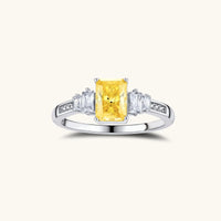 Yellow moissanite jewelry set with emerald-cut stones in sterling silver halo settings on white background.
