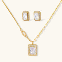 Gold-plated jewelry set with rectangular cubic zirconia stones in pave halo settings on cream background