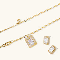 Gold-plated jewelry set with rectangular cubic zirconia stones in pave halo settings on cream background