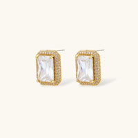 Gold-plated jewelry set with rectangular cubic zirconia stones in pave halo settings on cream background